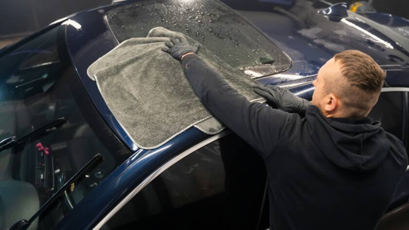 Car wash worker wipes the car after washing with microfiber towel. Professional car wash